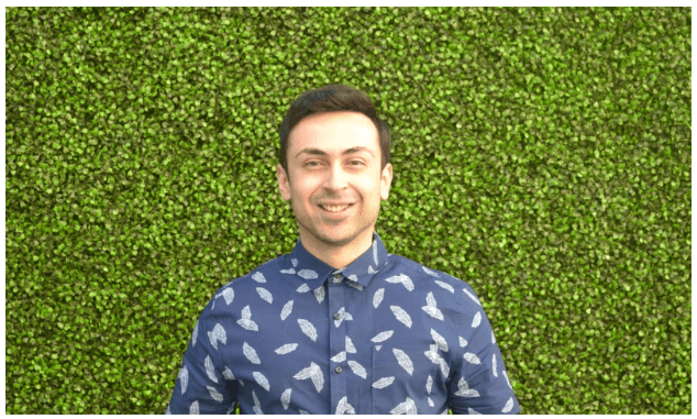 man in blue shirt standing in front of green shrub