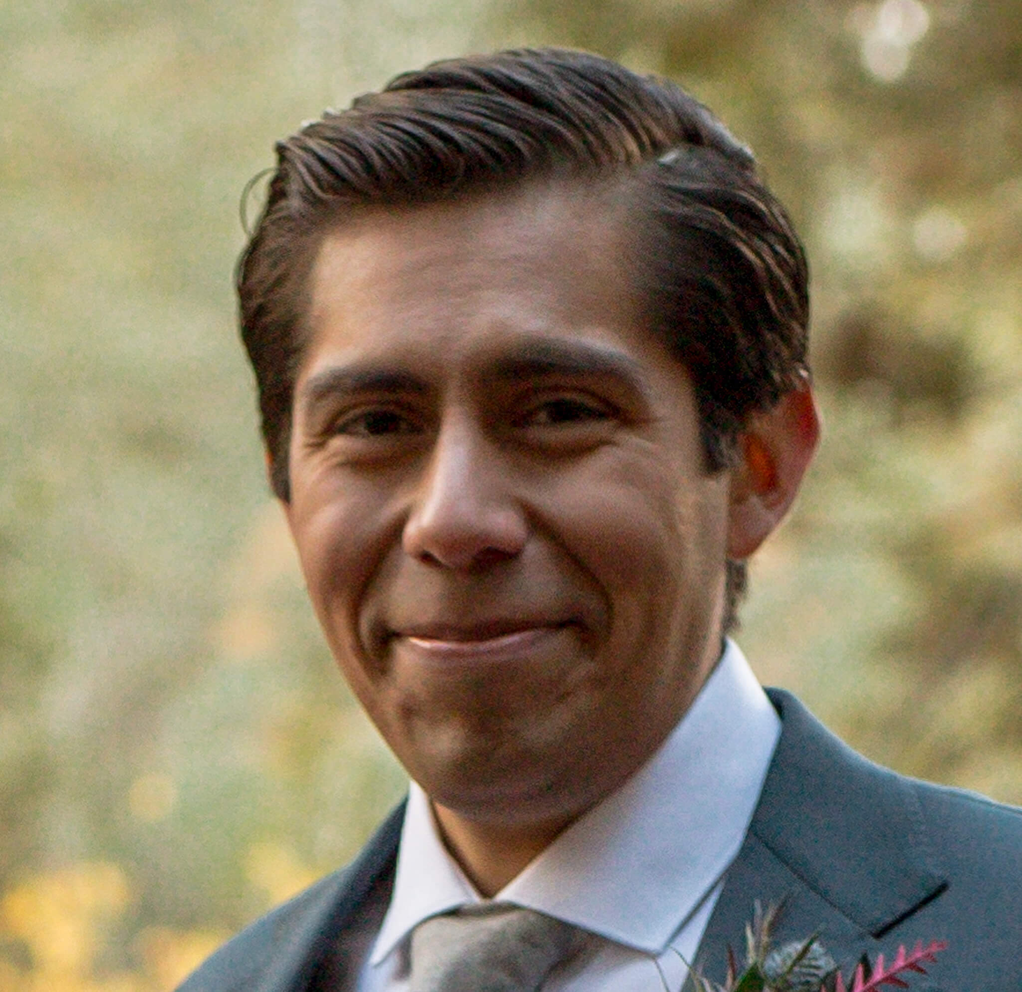 man with brown hair smiling, wearing suit