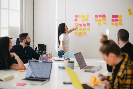 group of people meeting with stick it notes on wall