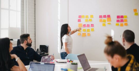 group of people meeting with stick it notes on wall